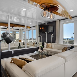 Sink into luxurious white sectional seating while savoring breathtaking ocean views through floor-to-ceiling windows in this elegantly designed coastal retreat.