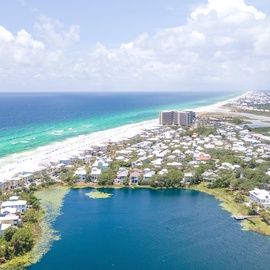Stunning aerial view showcasing pristine white sand beaches, turquoise Gulf waters, and coastal lake community.