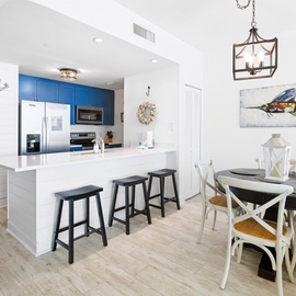 Your coastal-inspired kitchen and dining space features bright blue cabinets, modern appliances, and charming nautical artwork for memorable meals.