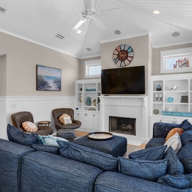 Sink into plush blue sectional seating where coastal charm meets comfort. Your cozy fireplace and vaulted ceilings create the perfect retreat.