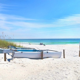 A pristine white sand beach with crystal-clear turquoise waters and charming fishing boats creates the perfect coastal escape.