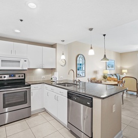 Your bright modern kitchen opens to the living area, perfect for preparing meals while enjoying ocean views through floor-to-ceiling windows.
