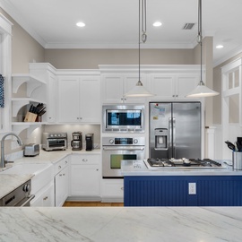 Your gourmet kitchen features marble countertops, stainless steel appliances, and a charming blue island perfect for preparing memorable meals together.