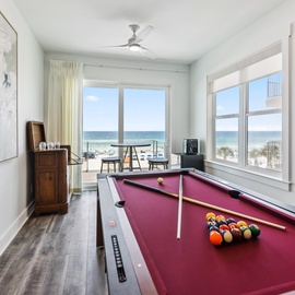 Challenge your friends to pool while enjoying stunning ocean views through floor-to-ceiling windows in this bright, coastal game room.