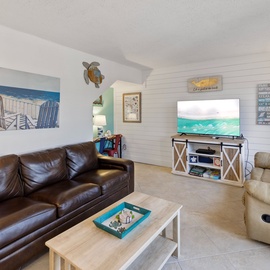 Sink into plush leather seating in your cozy living room, where beachy artwork and coastal charm create the perfect retreat.