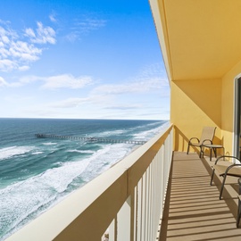 Oceanfront balcony featuring stunning sea views, comfortable seating, and direct beach access with nearby pier visible.