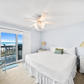 Wake up to ocean waves from your private balcony in this serene bedroom with soft blues and coastal charm.