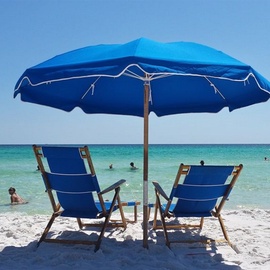 Pristine white sand beach with turquoise waters where you can unwind under blue umbrellas and soak up the coastal paradise.
