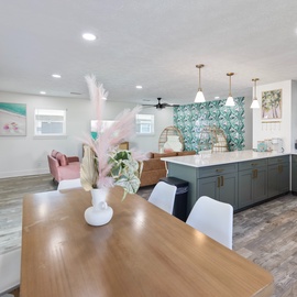 Stylish open-concept living space where the chef's kitchen flows seamlessly into dining and lounge areas. Coastal-chic design meets modern comfort with custom cabinetry and pendant lighting.