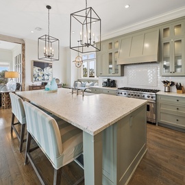 Your gourmet kitchen awaits with elegant sage cabinetry, marble countertops, and professional-grade appliances perfect for creating memorable meals together.