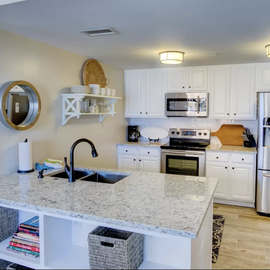 Cook your favorite meals in this bright, fully-equipped kitchen featuring granite countertops, stainless steel appliances, and thoughtful coastal touches.