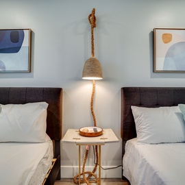 Unwind in your thoughtfully designed twin bedroom, featuring crisp linens, coastal artwork, and a charming rope pendant light creating the perfect ambiance.