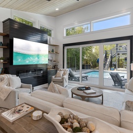 Sink into plush seating by your cozy fireplace while soaking in stunning pool views through floor-to-ceiling windows.