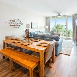 Relax in your spacious open-plan living space where warm wood tones meet coastal blues, all bathed in natural light from your private balcony.
