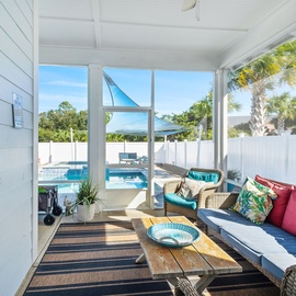 Unwind in your bright screened porch with tropical touches, watching the sparkling pool through expansive windows that frame lush palms.