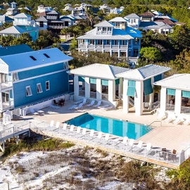 Stunning beachfront vacation home with private pool, colorful coastal architecture, and waterfront location in exclusive residential community.