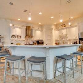 Step into your fully equipped kitchen where crisp white cabinets and elegant pendant lighting create the perfect space for preparing memorable meals.
