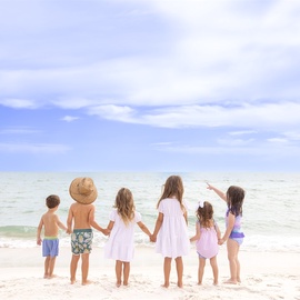 Children enjoying a beautiful beach day with pristine white sand and crystal-clear waters nearby.
