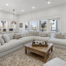 Sink into plush sectional seating where natural light flows through expansive windows, creating your perfect space to unwind and connect.