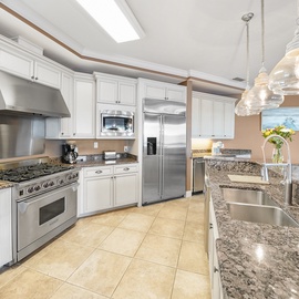 Prepare memorable meals in this chef-inspired kitchen featuring granite counters, premium appliances, and elegant pendant lighting.