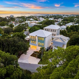 Stunning aerial view showcases this elegant coastal home nestled among mature trees in a charming neighborhood, just moments from the beach.