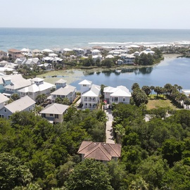 Coastal resort community featuring beachfront homes, lagoon waterways, and pristine sandy beaches stretching along the horizon.