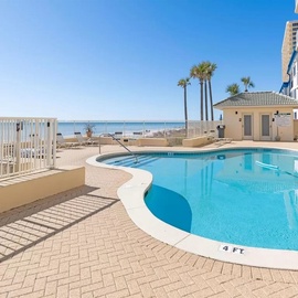 Beachfront pool area with sparkling blue water and direct ocean access steps away from the sandy shoreline.