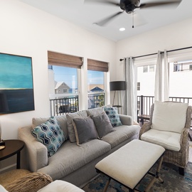 Sink into plush seating and feel the ceiling fan's gentle breeze as you unwind after your day. Multiple windows frame the neighborhood and balcony access invites you to step outside.