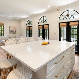 Your spacious kitchen island becomes the heart of your stay, where marble countertops and elegant arched windows create the perfect gathering space.