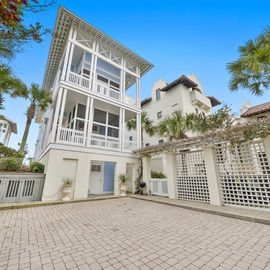 Charming coastal property featuring classic architecture with wraparound balconies, surrounded by tropical palms in a peaceful residential setting.