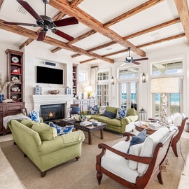Sink into plush seating beneath stunning exposed beams while your fireplace crackles and ocean views unfold beyond the windows.