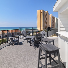 A spacious rooftop terrace with Adirondack chairs and bar seating offers stunning ocean views, perfect for your morning coffee or sunset cocktails over the turquoise water.