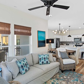 Relax in your bright, coastal-inspired living space where teal accents and bamboo blinds frame ocean views from your private balcony.