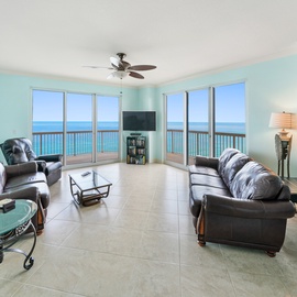 Unwind in your oceanfront living room with panoramic sea views. Comfortable leather seating and ceiling fan create the perfect coastal retreat.