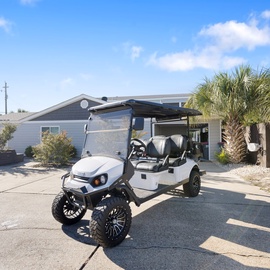 Modern beach house with golf cart for easy coastal exploration and tropical landscaping.