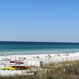 Pristine white sand beach with crystal-clear turquoise waters and kayaks ready for waterfront adventures during your coastal getaway.