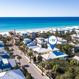 Charming beach community featuring colorful coastal homes nestled among palm trees, just steps from pristine turquoise waters.