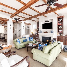 Sink into plush green sofas beneath stunning exposed beams, where your fireplace crackles and thoughtful touches create your perfect retreat.