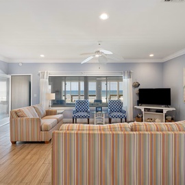 Relax in your spacious living room with colorful striped furniture, coastal views, and all the comforts of home.