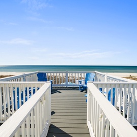 Relax in bright blue chairs on your private deck, where ocean breezes and stunning beach views create the perfect coastal escape.