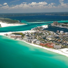 Stunning aerial view of pristine emerald waters meeting white sand beaches and coastal development along this beautiful shoreline destination.