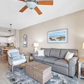 Relax in your bright open living space with coastal artwork and plush seating that flows seamlessly into the modern kitchen.