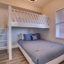 Your clever bunk bed setup maximizes space while keeping everyone comfortable, with cozy blue linens and warm natural light streaming through.