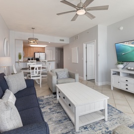 Unwind in your bright, coastal-themed living space with plush seating, modern entertainment, and a seamless flow to the kitchen.