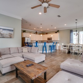Relax in your spacious open-concept living area where coastal charm meets modern comfort, featuring plush seating and a fully-equipped kitchen perfect for your getaway.