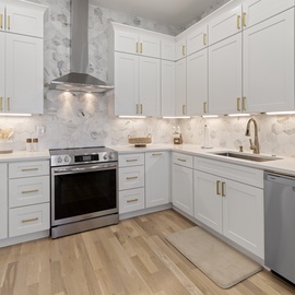 Step into this bright, modern kitchen with pristine white cabinets, elegant gold hardware, and gleaming marble backsplash that creates your perfect culinary haven.