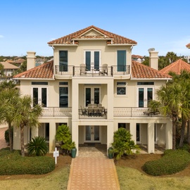 Mediterranean-style vacation home with terracotta tile roof and palm trees in an upscale coastal neighborhood.