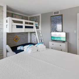 You'll love this stylish bedroom featuring a cozy double bed and fun bunk beds, perfect for families. Ocean-themed decor and modern amenities create your ideal beach getaway retreat.