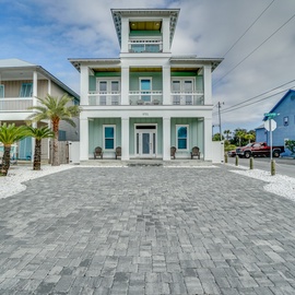 Charming coastal home with spacious paved driveway and tropical landscaping in a vibrant beach community neighborhood.