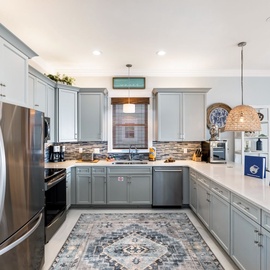 Your spacious kitchen awaits with gleaming countertops, modern appliances, and woven pendant lights creating the perfect spot for morning coffee or holiday feasts.